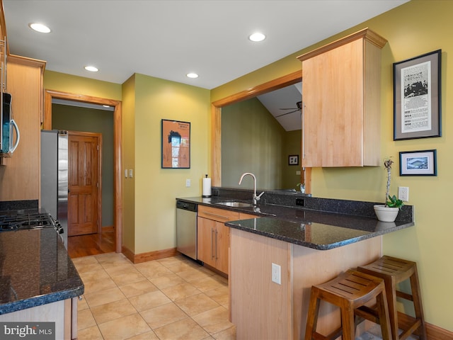 kitchen with a breakfast bar area, recessed lighting, appliances with stainless steel finishes, a peninsula, and a sink