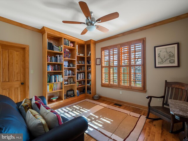 living area featuring visible vents, ornamental molding, baseboards, and wood finished floors