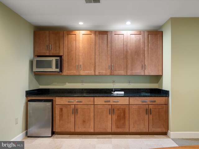 kitchen with recessed lighting, baseboards, appliances with stainless steel finishes, and dark stone countertops