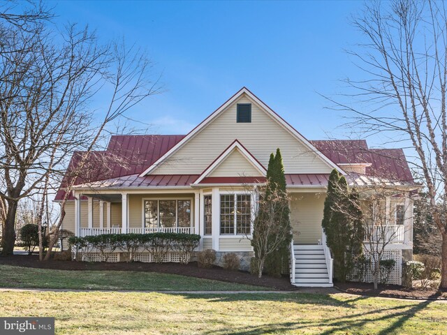 view of front of property featuring a standing seam roof, a porch, a front lawn, and metal roof