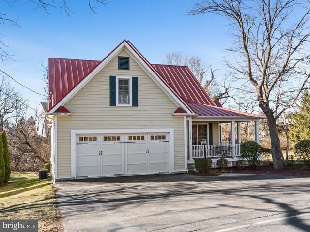 view of front of house featuring aphalt driveway, a porch, central AC, metal roof, and a garage