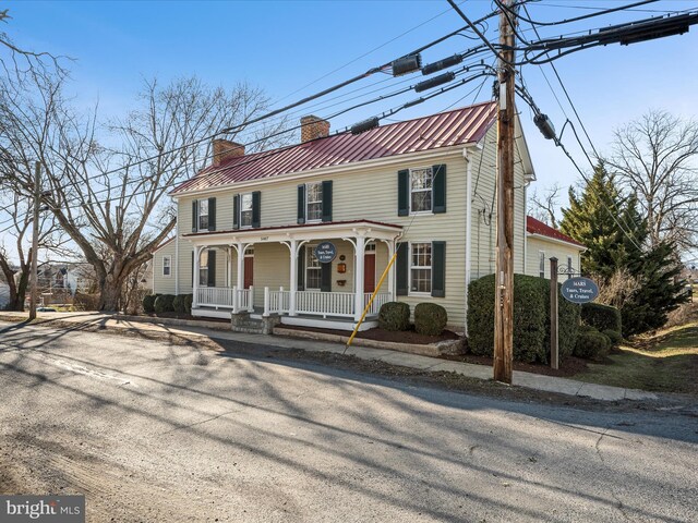 view of front of house featuring a porch, a chimney, and metal roof