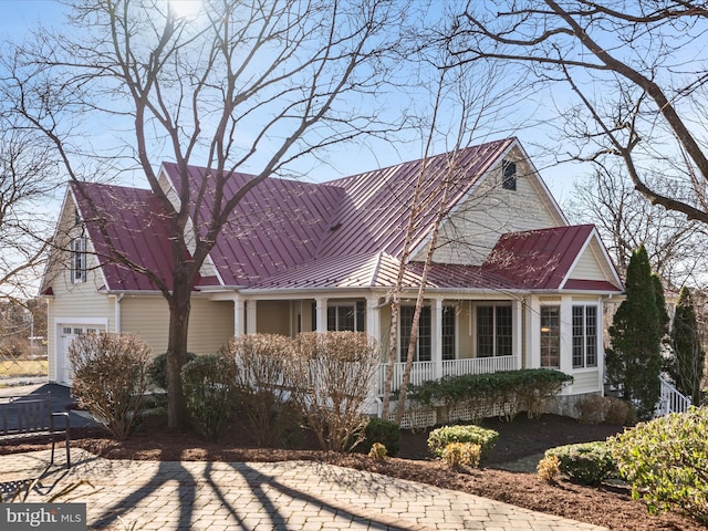 view of front of home with a standing seam roof, a porch, driveway, and metal roof