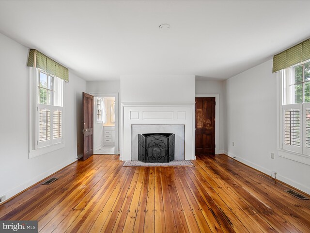 unfurnished living room with visible vents, a fireplace with flush hearth, and wood-type flooring