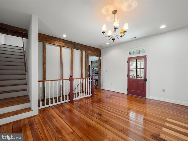 empty room featuring stairs, a notable chandelier, recessed lighting, and wood-type flooring