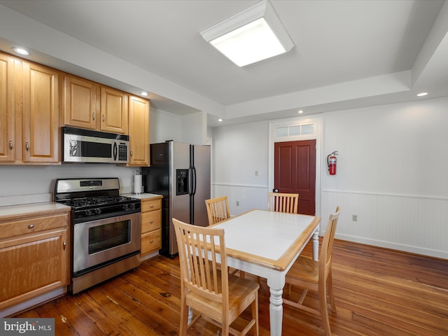 kitchen with dark wood finished floors, recessed lighting, wainscoting, and stainless steel appliances