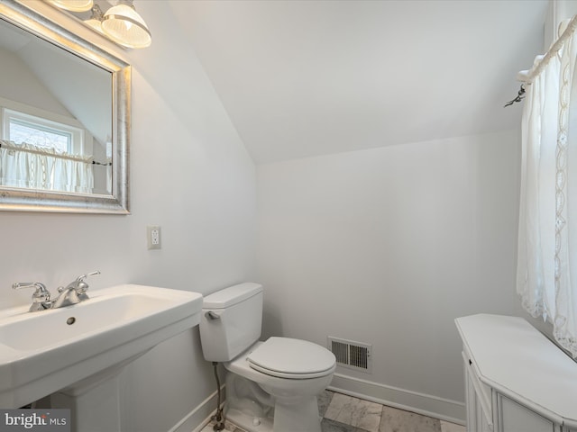 bathroom featuring visible vents, toilet, marble finish floor, baseboards, and vaulted ceiling