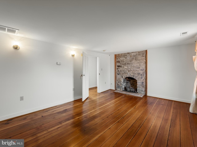 unfurnished living room featuring visible vents, wood-type flooring, baseboards, and a fireplace