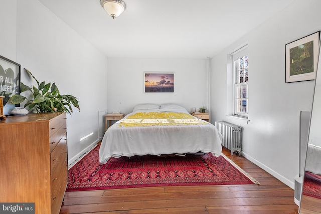 bedroom featuring baseboards, radiator heating unit, and hardwood / wood-style flooring