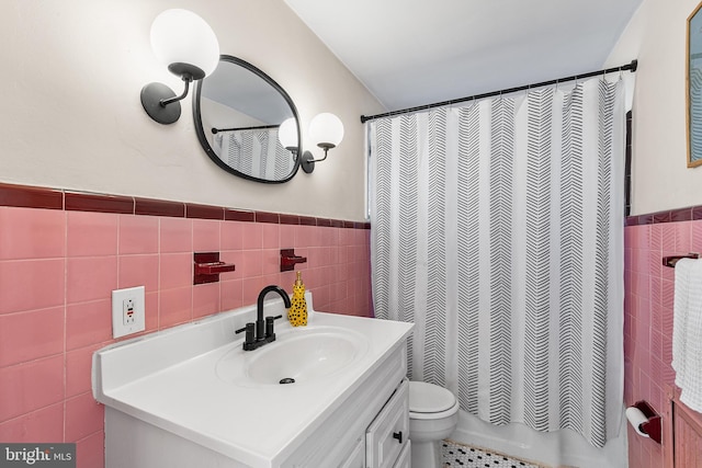 bathroom with wainscoting, toilet, tile walls, and vanity