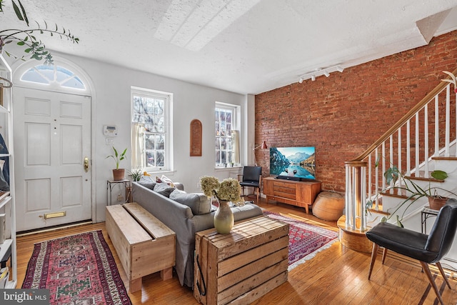 living room featuring a textured ceiling, stairs, and wood-type flooring