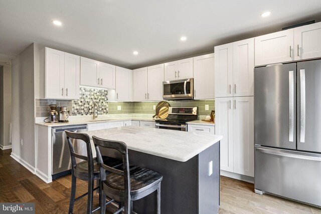 kitchen featuring a sink, stainless steel appliances, a kitchen bar, and wood finished floors