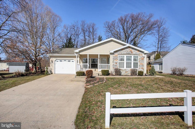 view of front facade with stone siding, a porch, concrete driveway, and a front yard