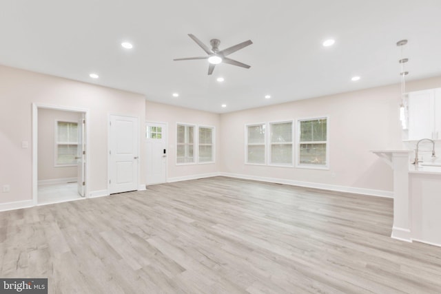 unfurnished living room with ceiling fan, recessed lighting, light wood-type flooring, and a sink