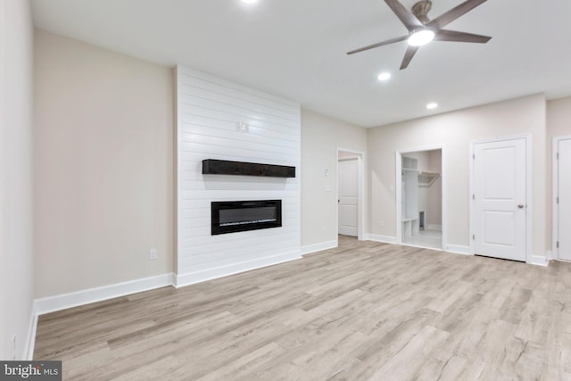 unfurnished living room featuring baseboards, ceiling fan, a fireplace, and light wood finished floors