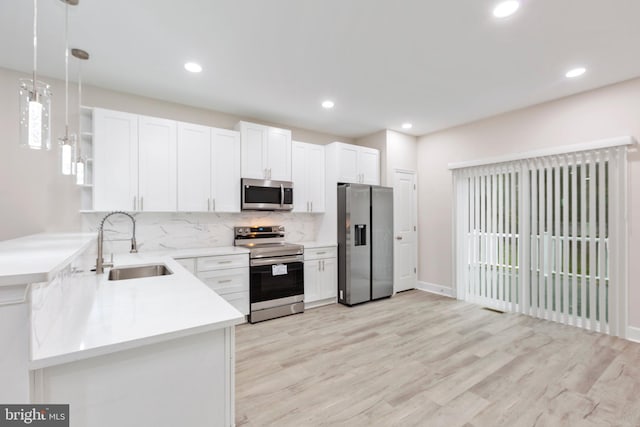 kitchen with open shelves, pendant lighting, decorative backsplash, appliances with stainless steel finishes, and a sink