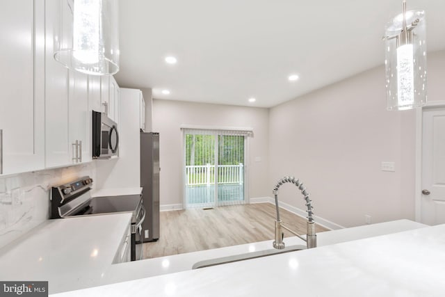 kitchen with tasteful backsplash, light countertops, white cabinets, stainless steel appliances, and a sink