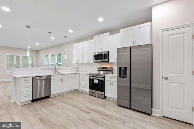 kitchen with decorative backsplash, light wood finished floors, appliances with stainless steel finishes, and a sink