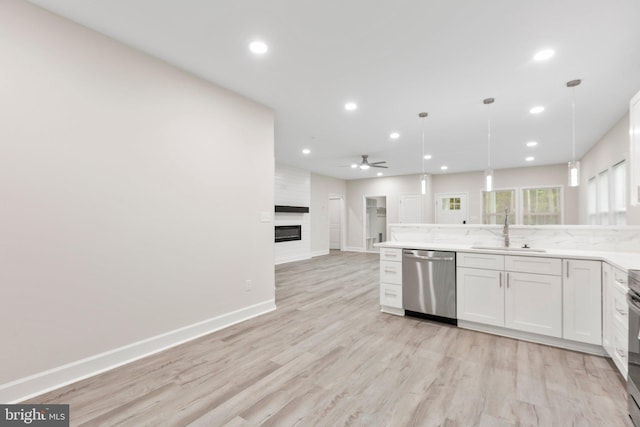 kitchen with a large fireplace, open floor plan, dishwasher, recessed lighting, and a sink