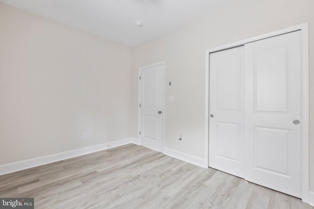 unfurnished bedroom with a closet, baseboards, and light wood finished floors