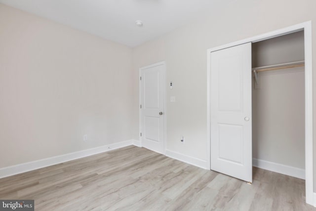 unfurnished bedroom with a closet, light wood-type flooring, and baseboards