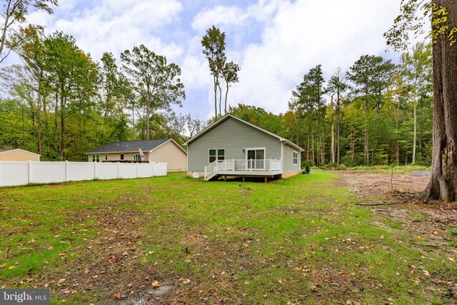 back of property featuring a wooden deck, a yard, and fence