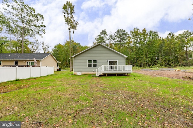 rear view of house featuring a lawn, a deck, and fence