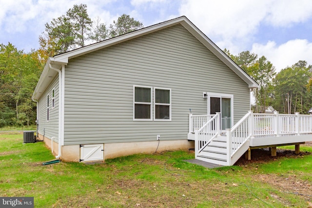 back of property with cooling unit, a lawn, and a wooden deck