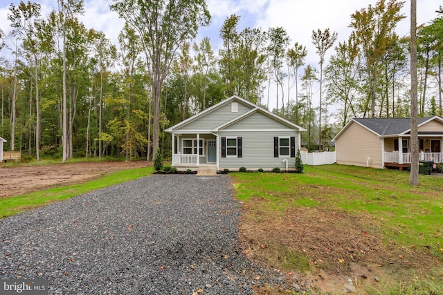 view of front facade featuring gravel driveway, a porch, and a front lawn