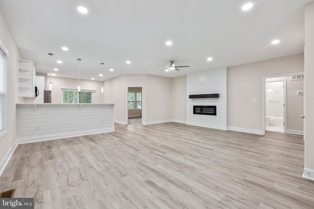 unfurnished living room with recessed lighting, a large fireplace, and light wood finished floors