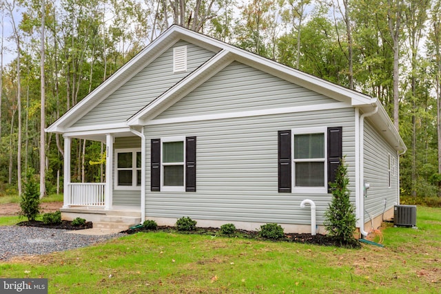 view of front facade featuring covered porch, central AC, and a front yard