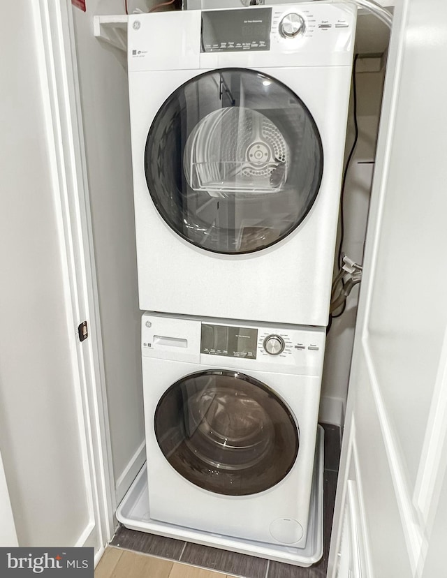 laundry room featuring laundry area, stacked washer / drying machine, and wood tiled floor