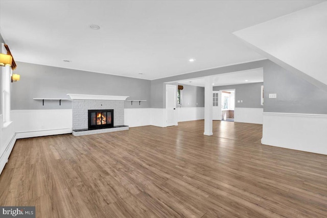 unfurnished living room featuring recessed lighting, wainscoting, wood finished floors, and a fireplace