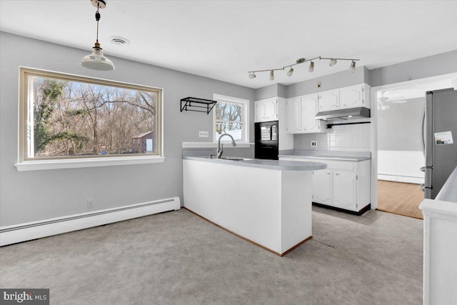 kitchen featuring a baseboard heating unit, black microwave, under cabinet range hood, freestanding refrigerator, and a sink