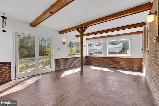 interior space with beamed ceiling, wood finished floors, brick wall, and wainscoting