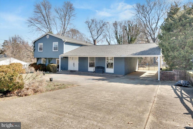 view of front of home featuring brick siding, an attached carport, driveway, and a shingled roof