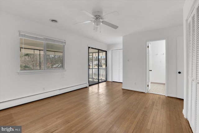 empty room with visible vents, ceiling fan, baseboards, hardwood / wood-style flooring, and a baseboard radiator