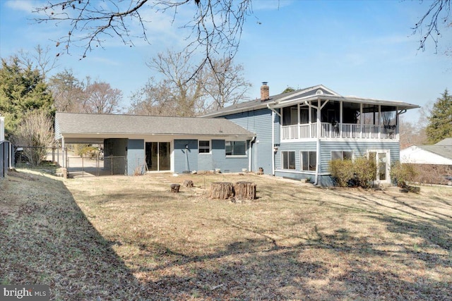 back of property with fence, a yard, a sunroom, a carport, and a chimney