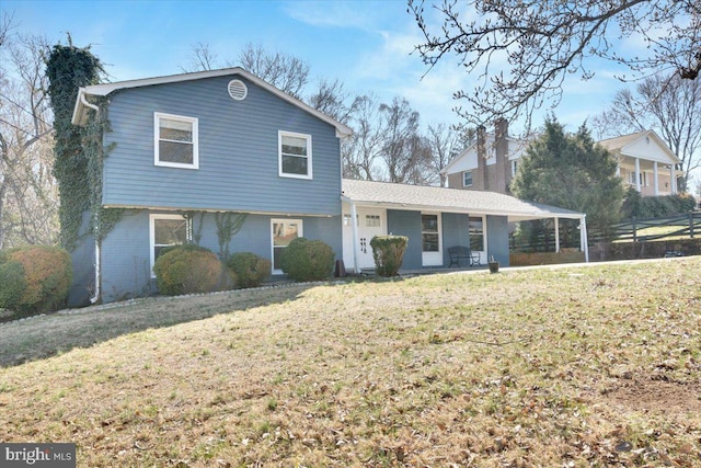 tri-level home with brick siding, a chimney, and a front lawn