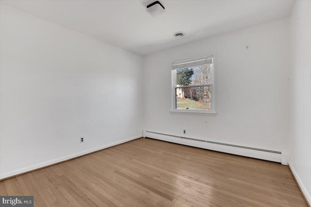 spare room with visible vents, wood finished floors, baseboards, and a baseboard radiator