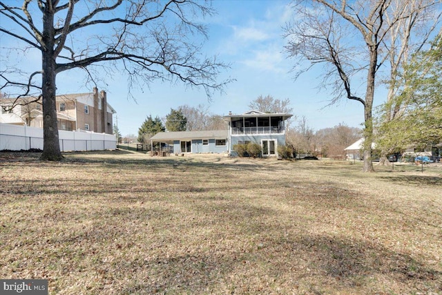 rear view of property with a sunroom, a lawn, and fence