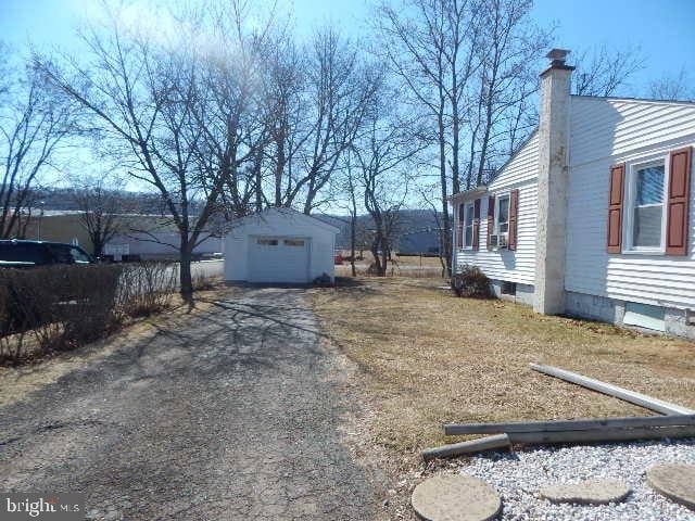 view of yard with a garage, an outdoor structure, and driveway