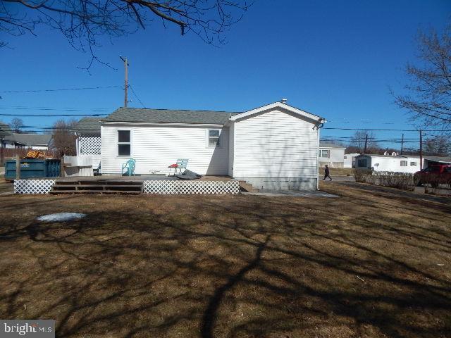 rear view of house featuring a lawn and a wooden deck