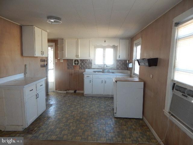 kitchen featuring a sink, decorative backsplash, light countertops, and white cabinetry