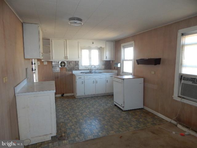 kitchen with a sink, white cabinetry, fridge, and light countertops