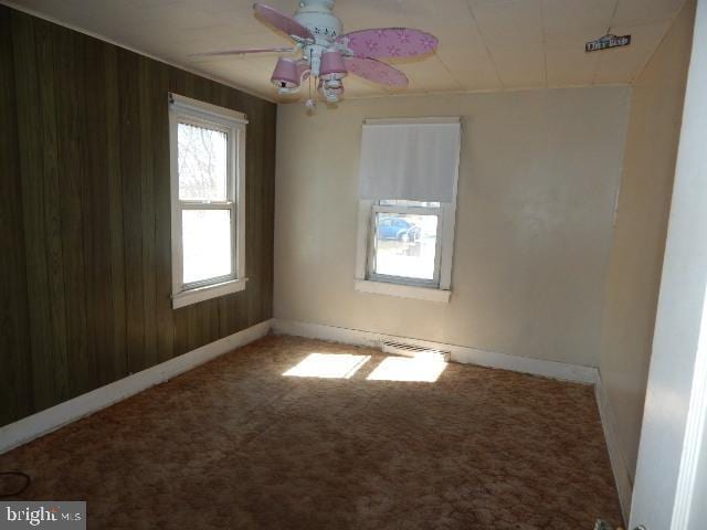 empty room with carpet flooring, a ceiling fan, and baseboards