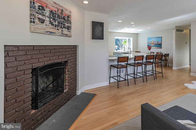 living area with visible vents, baseboards, recessed lighting, a fireplace, and wood finished floors