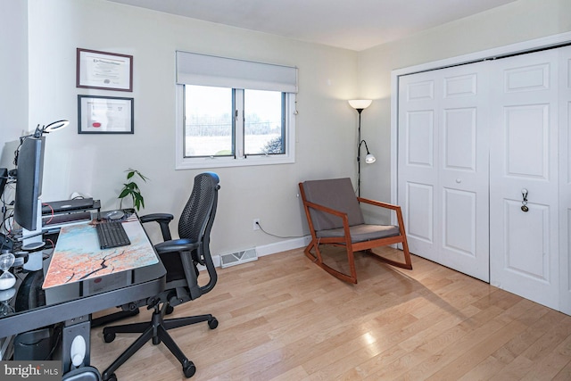 office area featuring visible vents, light wood-style flooring, and baseboards