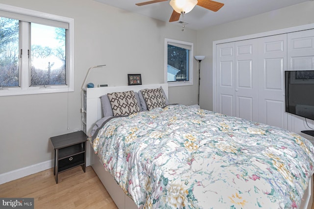 bedroom with light wood-style flooring, baseboards, a closet, and ceiling fan