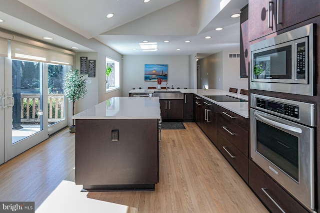 kitchen featuring dark brown cabinets, appliances with stainless steel finishes, a center island, and light countertops